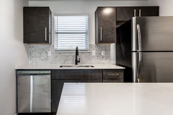 A modern kitchen with a stainless steel refrigerator and a marble backsplash
